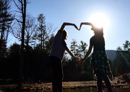 Two girls making a heart shape with their arms